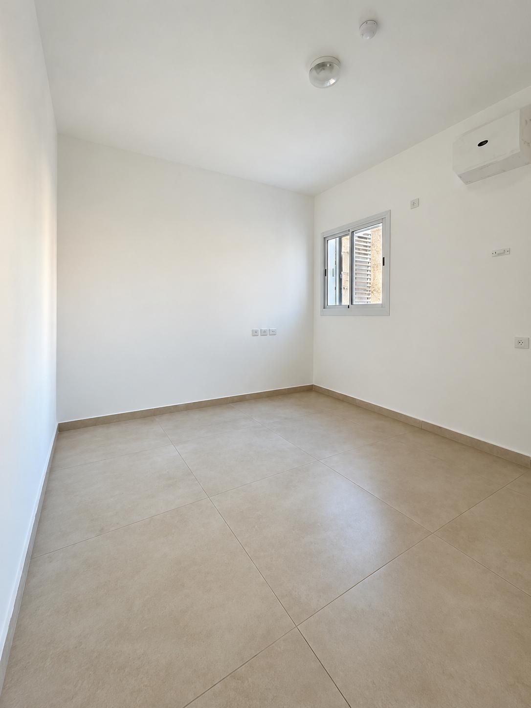 1002777832 Frankel apartment bedroom with a tiled floor and window.
