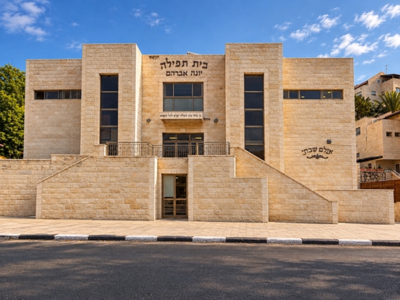 Exterior of Beis Tefillah Yonah Avraham, with stone facade and entrance steps.