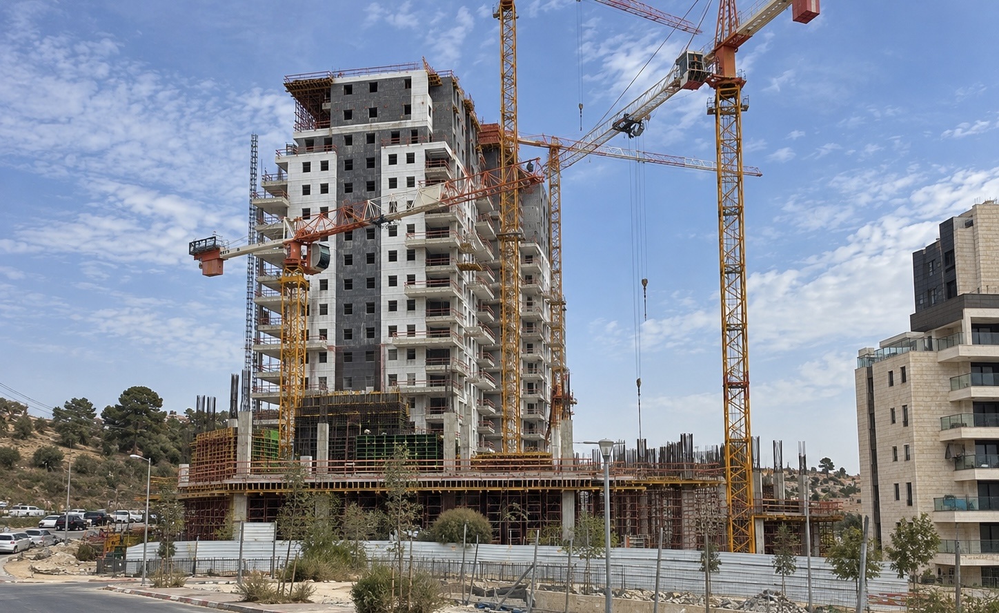 Multi-story buildings under construction with cranes in Neve Shamir.